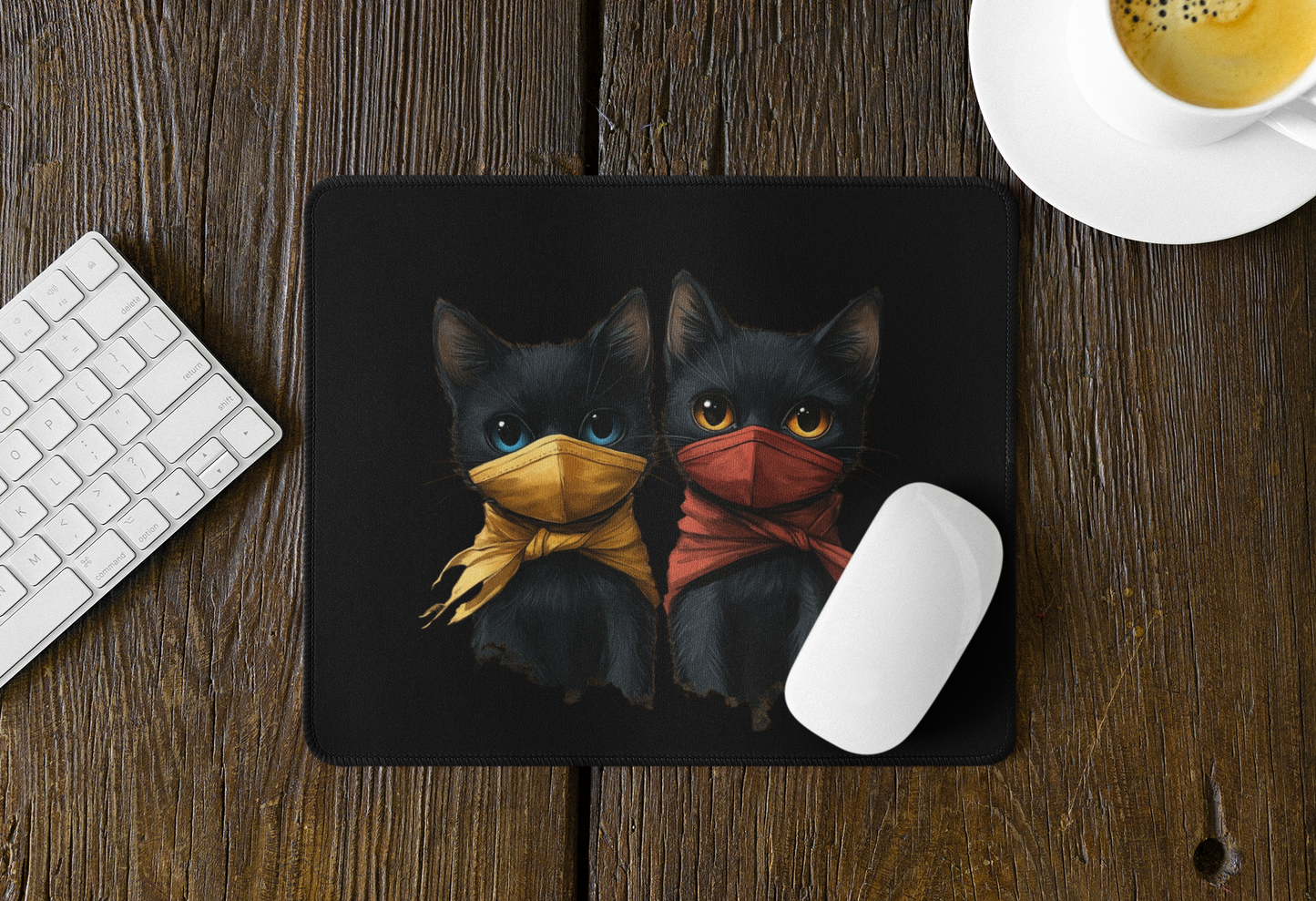 A rectangular black mouse pad on a rustic wooden desk, featuring an illustration of two black cats wearing face masks. 